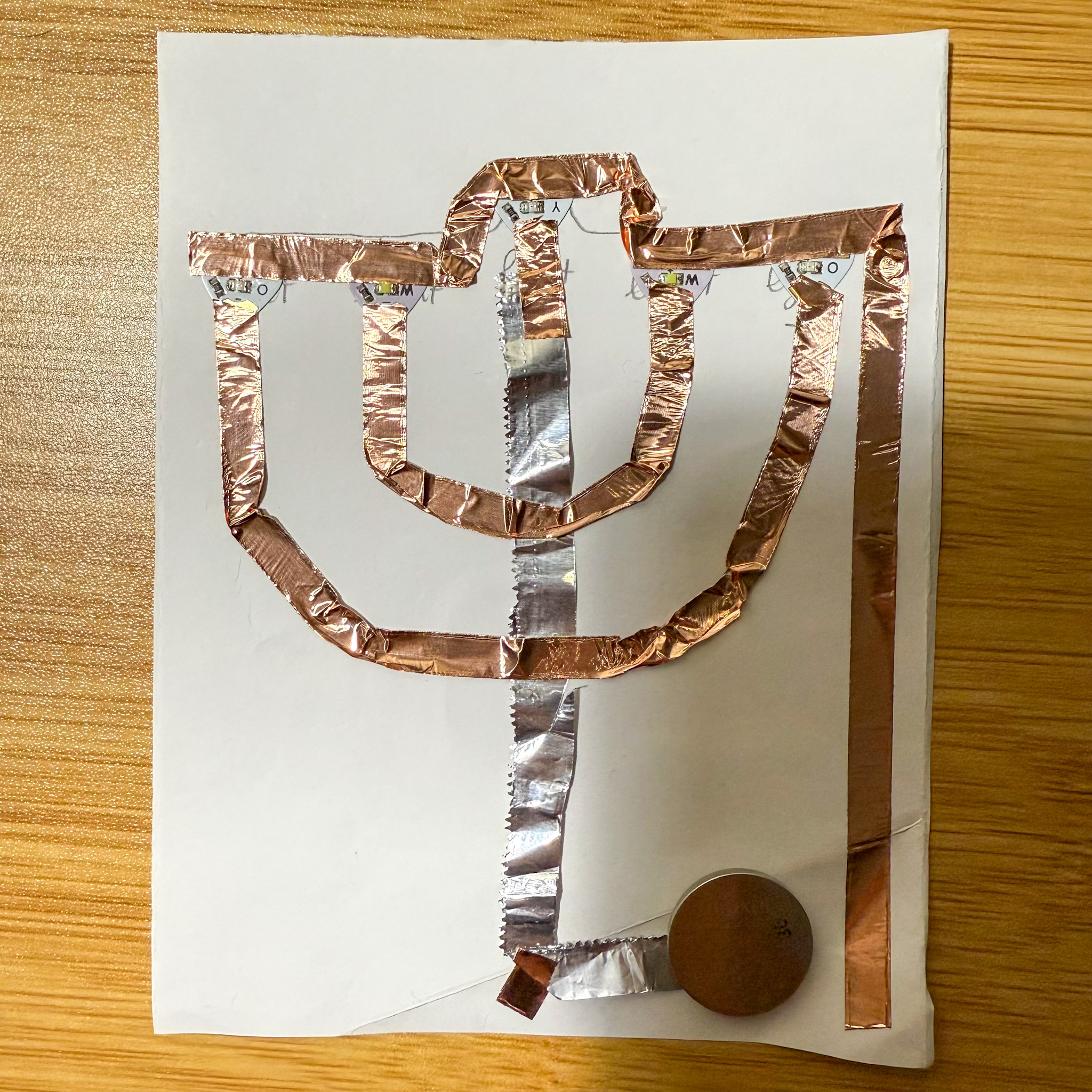 Placing the conductive materials and battery on the circuit. For this circuit, I used foil and conductive tapes.